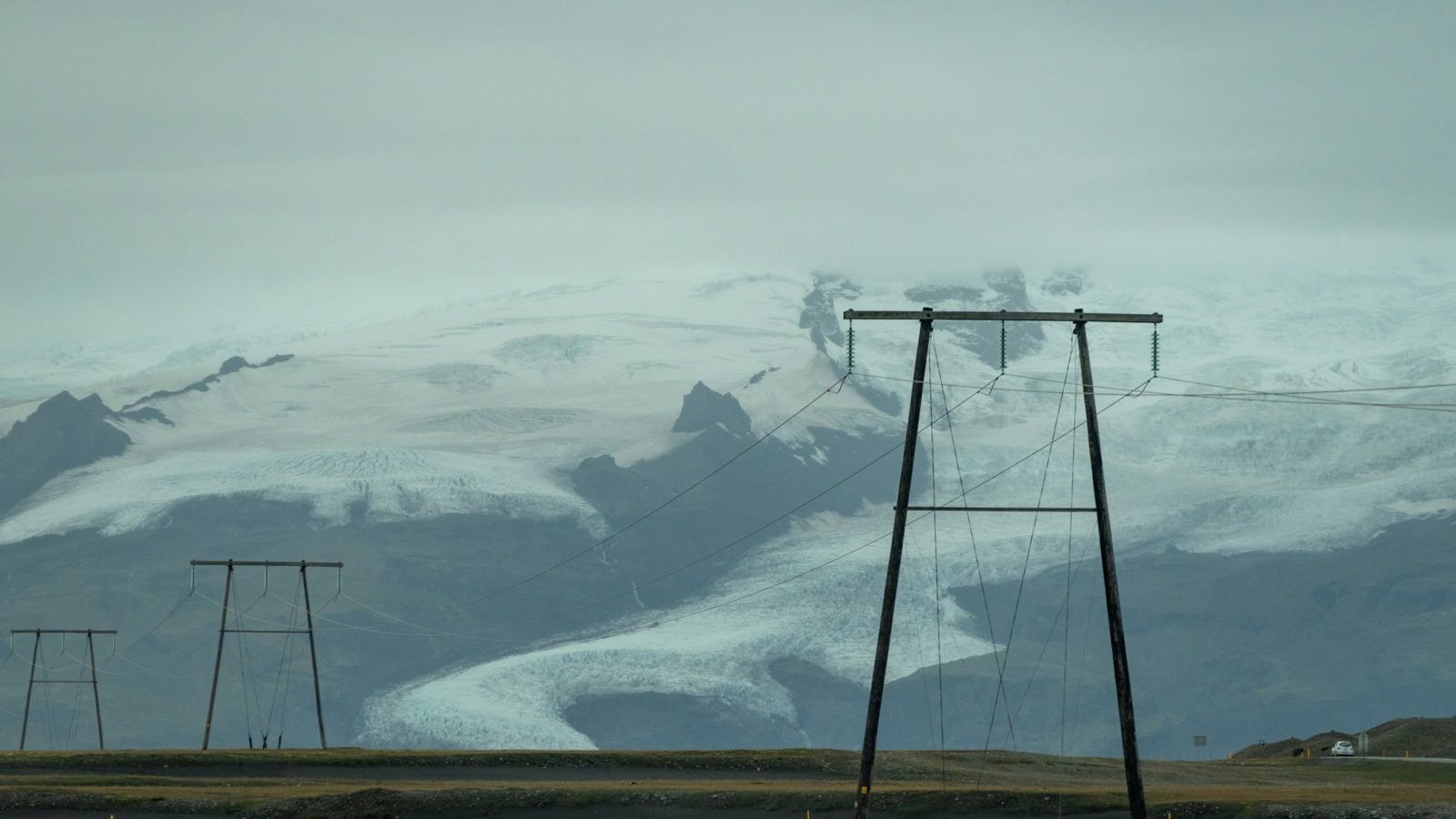 Power line in front of a snow-covered glacier