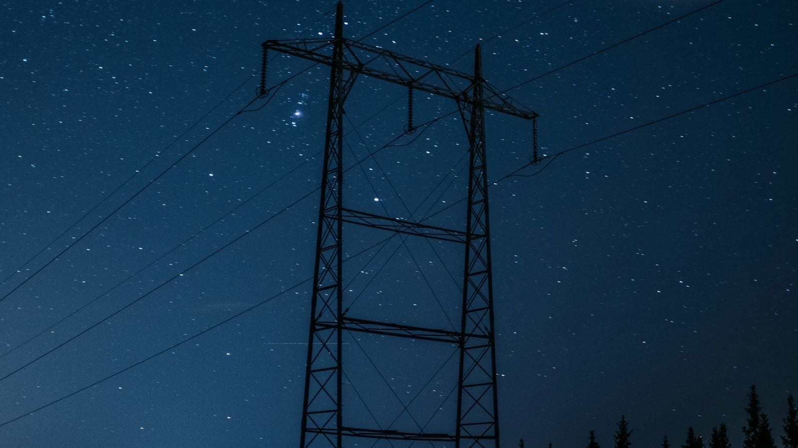 Transmission tower against a starry winter sky in Norway